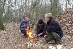 Fire-lighting in front of improvised shelter on a bushcraft course