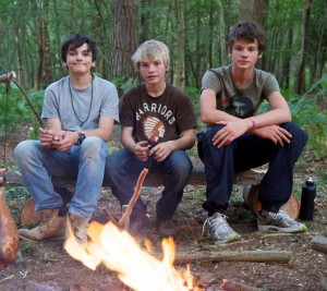 Three boys in front of a campfire on a junior bushcraft course