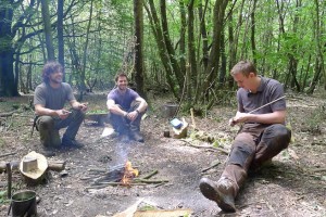 Intermediate bushcraft students around campfire in the middle of woods