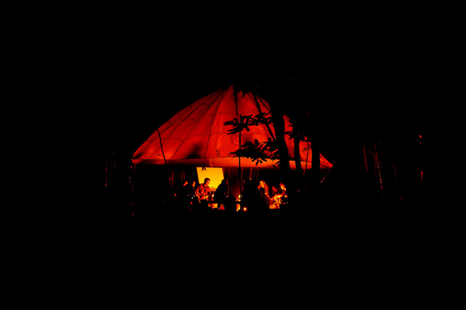 Parachute shelter illuminated by firelight