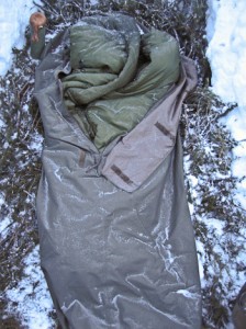 Bivvy bag and sleeping bag covered in frost and light snow.