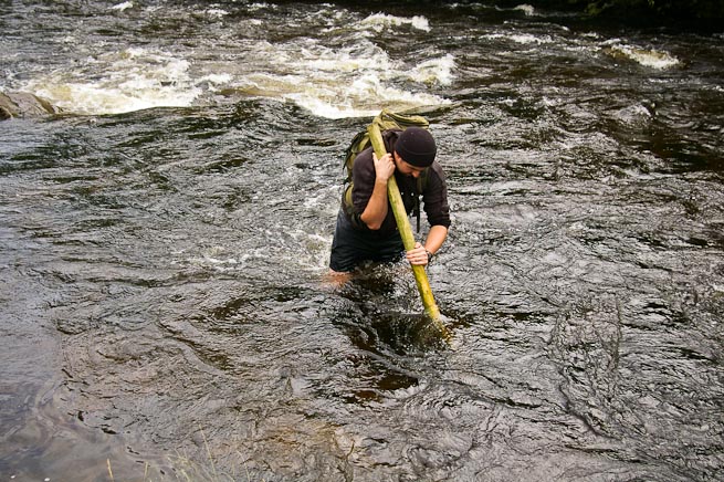 Crossing a river while wearing a backpack
