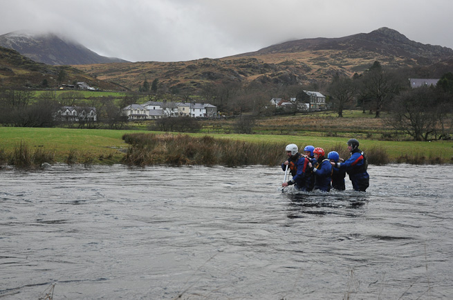Team of people wading a river in a wedge shape