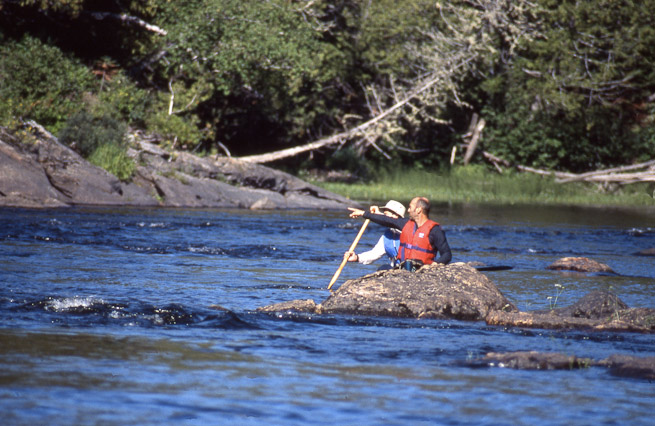 Men in canoe, pointing and discussing wilderness river