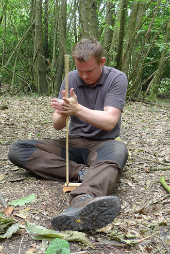 Student of bushcraft getting to grips with hand-drill