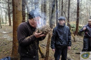 Man blowing smoke from bracken in the woods