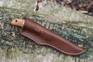Small bushcraft knife in a chestnut brown leather sheath