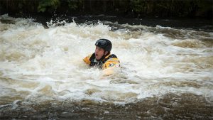 Man swimming out of recirculation hydraulic in river in Wales