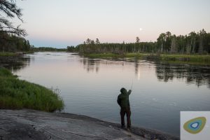 Man standing in wilderness casting fishing rod