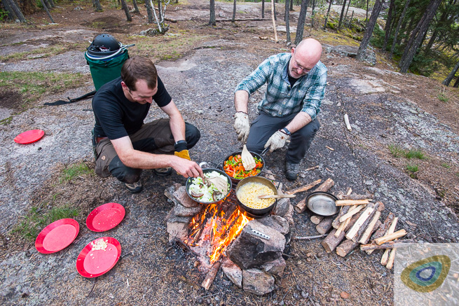 Two guys cooking on a campfire