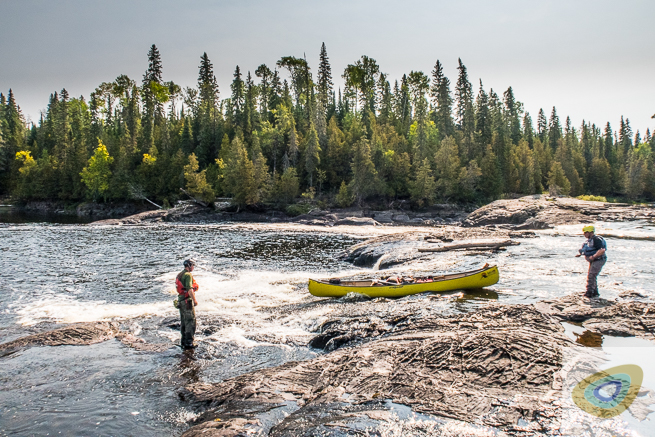 Two men lining a 17 ft canoe on rocky rapids on the Missinaibi river