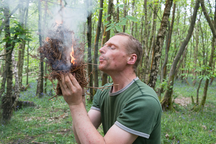 Man blowing bundle of bracken into flame on a bushcraft course