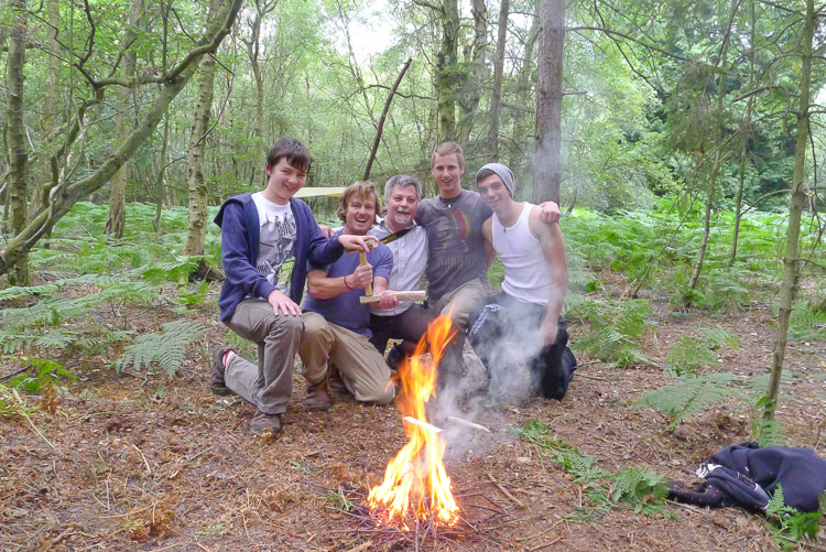 Smiling participants following their bow drill friction fire success on a Frontier Bushcraft course.
