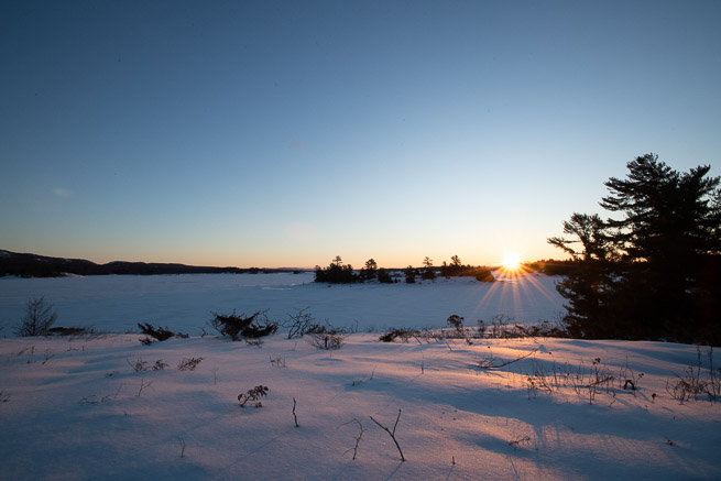 Sun rising over horizon of winter landscape