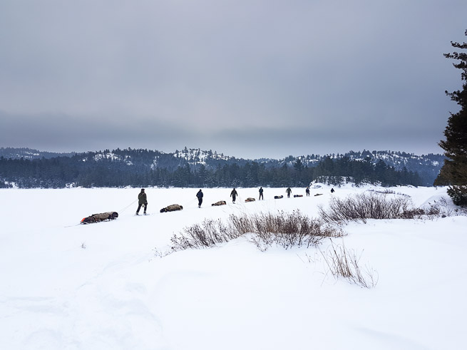 Snow walkers on snowshoes with toboggans head into the wilds