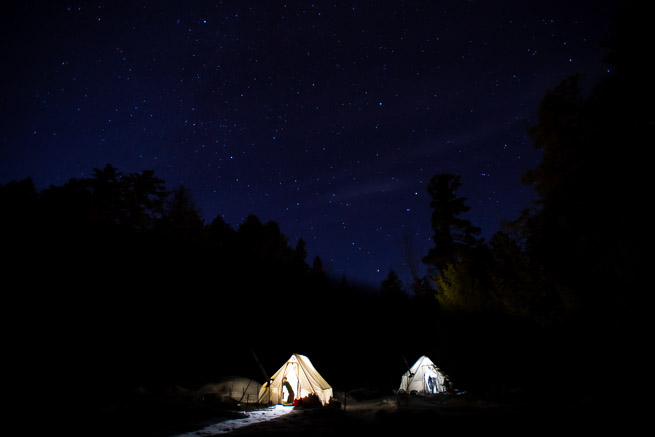Canvas tents illuminated from inside, under starry sky